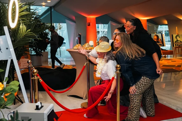 Een groep collega's staat lachend voor de Magic Mirror, klaar om hun foto te maken. Dit doen ze met de Papri Photobooths.