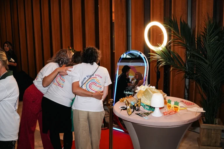 Groep vrienden poseert lachend voor de Papri photobooths tijdens een feest. Ze hebben gekozen voor het pakket Magic Mirror Standaard.