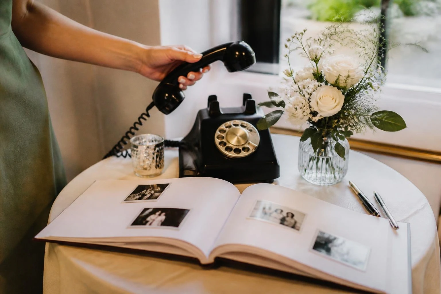 Gast spreekt een bericht in op een vintage telefoon als audio-gastenboek, naast een gastenboek met polaroids